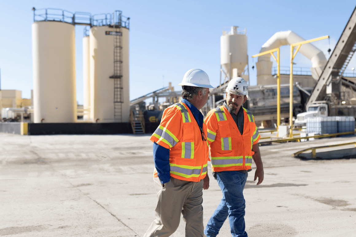 two men walk walking through an aggregate plant 