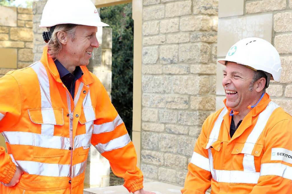 construction worker in hardhat laughing with coworker